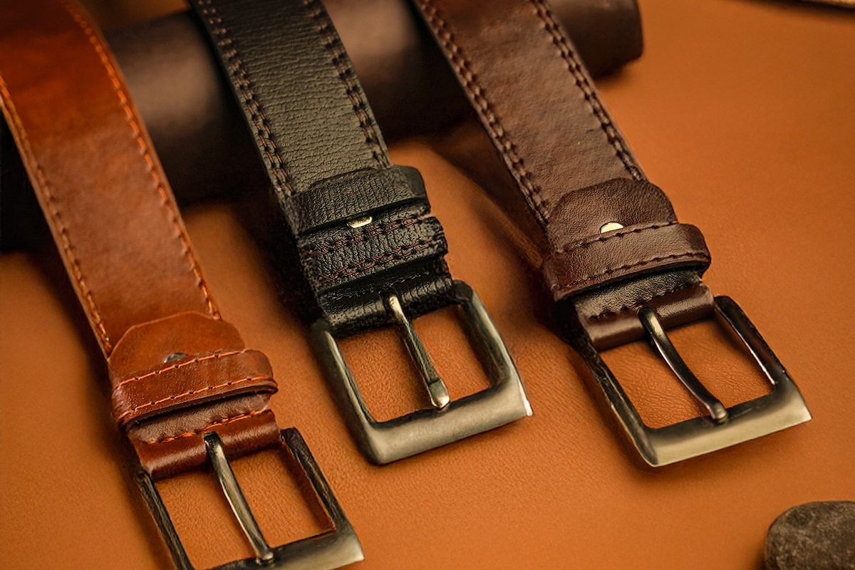 A full-grain leather belt coiled on a wooden table
