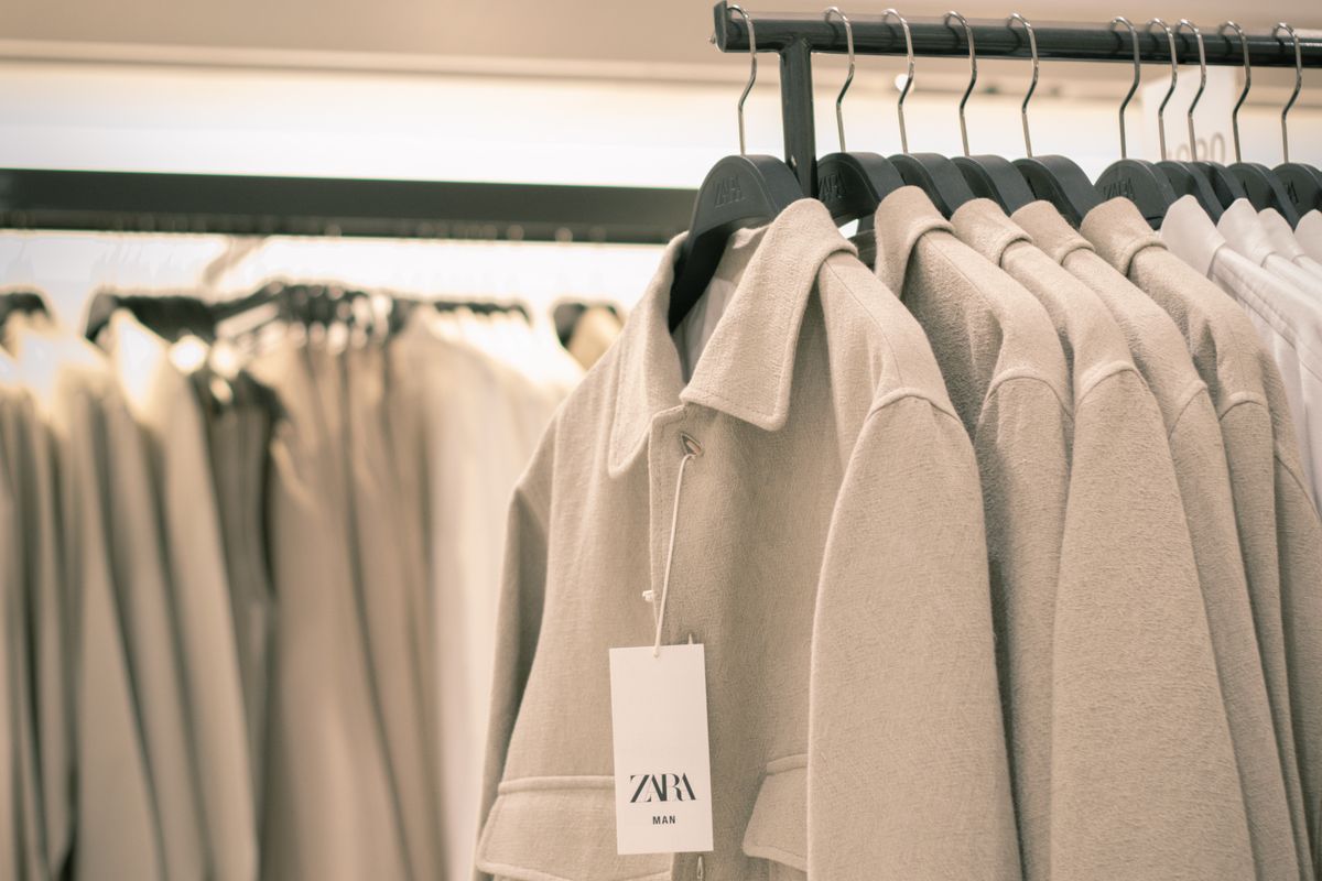A compact rail of neutral tailored workwear pieces on wooden hangers