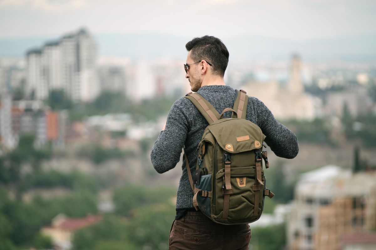 A compact travel backpack stowed beneath an airplane seat in front